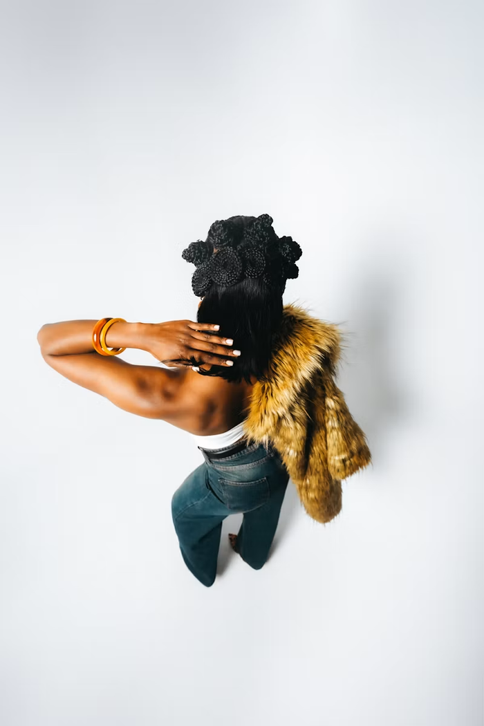 Braided crown with straight dark hair, gold bangles and a fur jacket