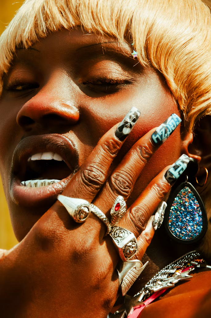 Blonde bob with a grill, statement nails and stacked rings