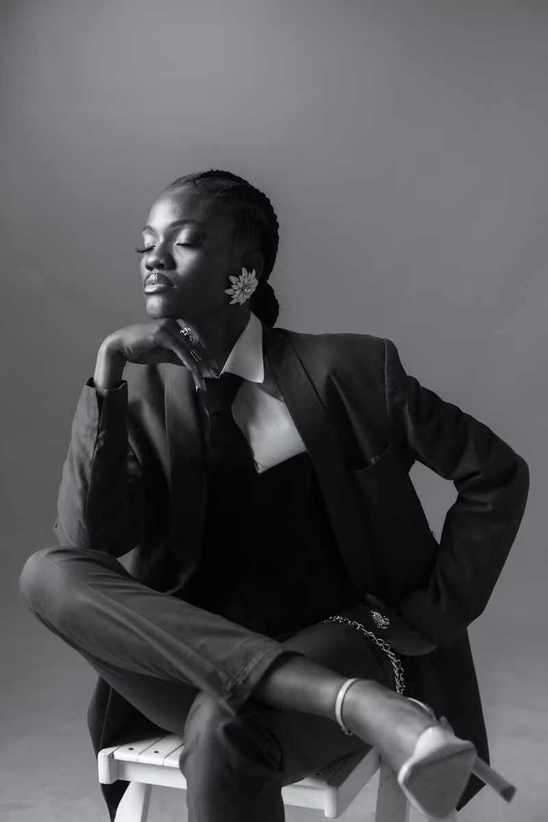 Black-and-white portrait with braids, a suit and floral earrings