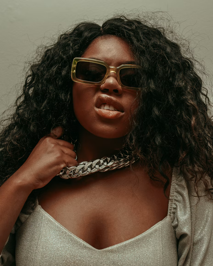Curly black hair, gold-toned sunglasses and chunky silver chain