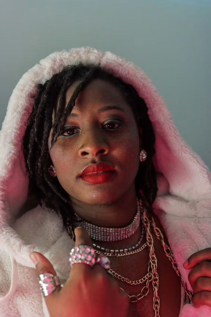 Locs framed by a fur hood, layered chains and statement rings