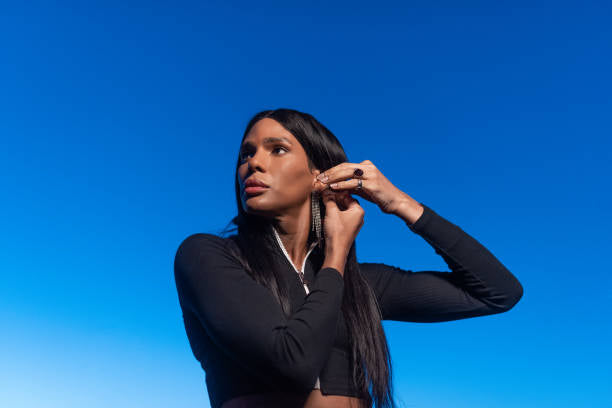 Long straight dark hair and statement earrings against blue sky