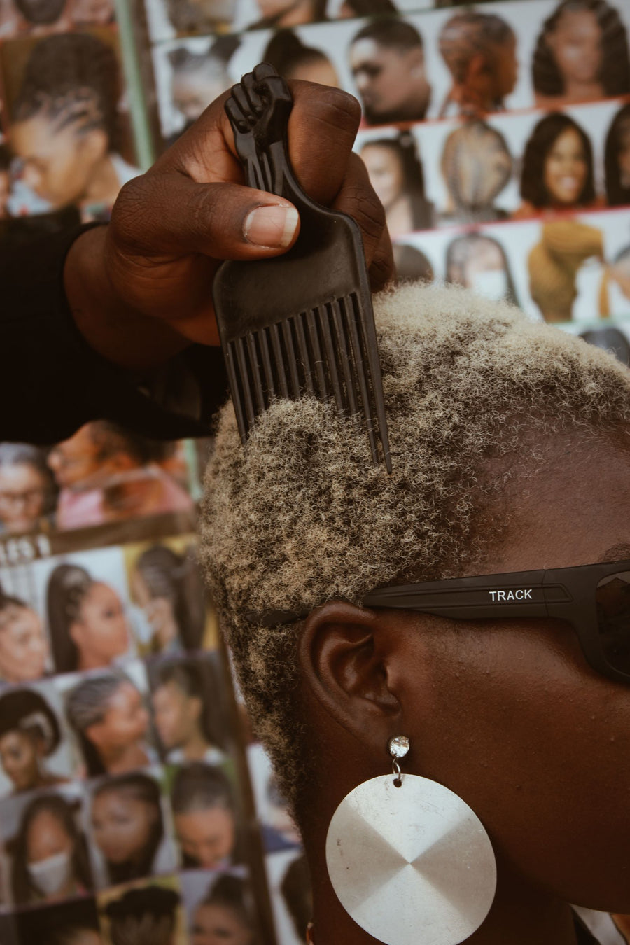 Raised-fist afro pick in blonde natural hair with a silver earring